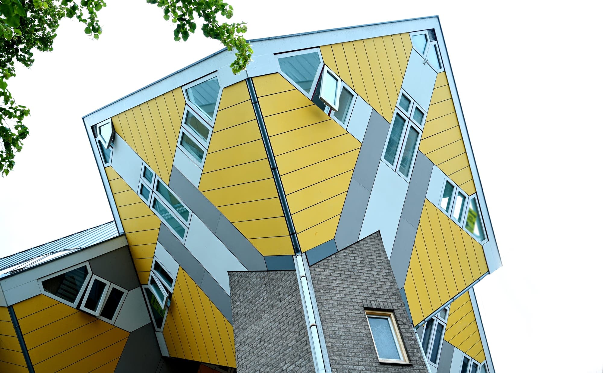 The Cube Houses (Kubuswoningen) in Rotterdam, seen from below against a bright sky.